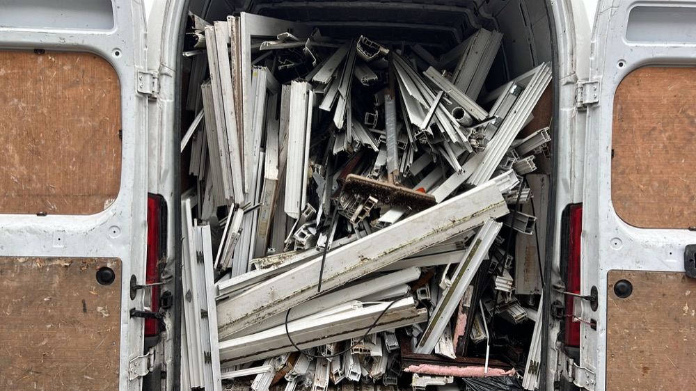 Old uPVC window frames loaded in a collection van