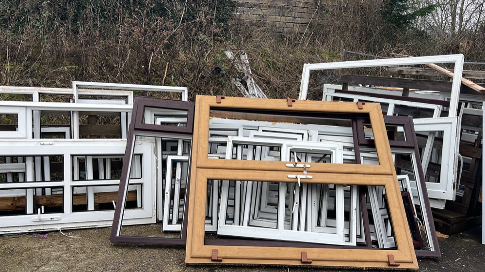 Stockpile of mixed-colour uPVC window frames including woodgrain and rosewood foiled